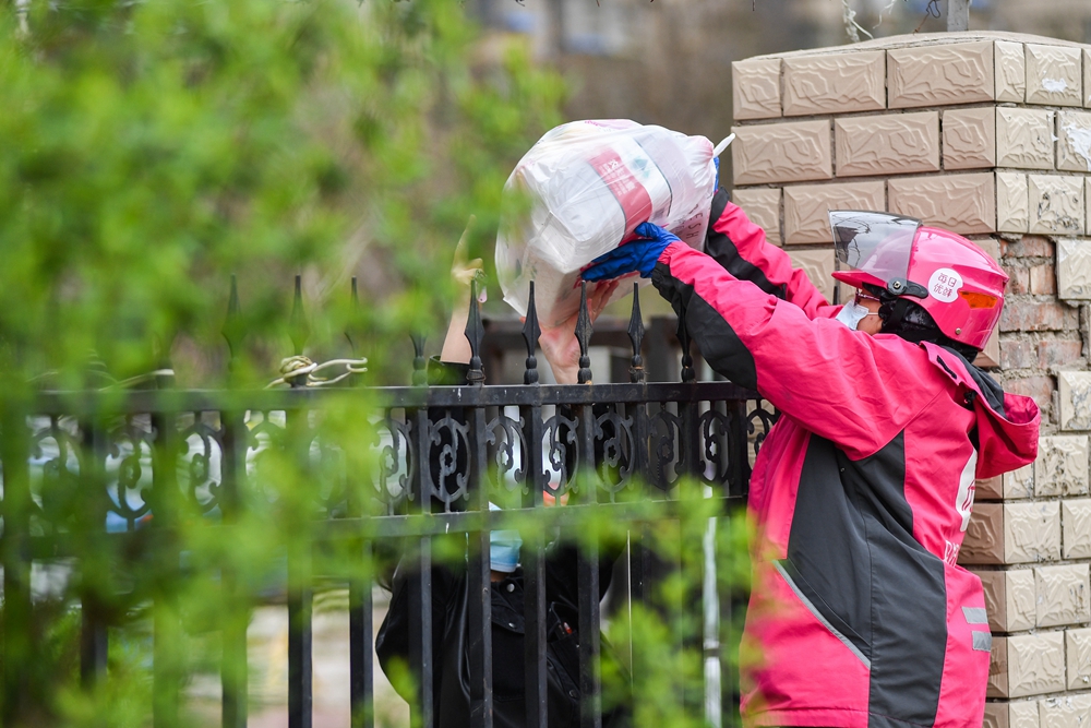 2020年3月26日，北京，由于疫情期间小区封闭，赵蕊隔着铁栅栏给用户送货。.JPG