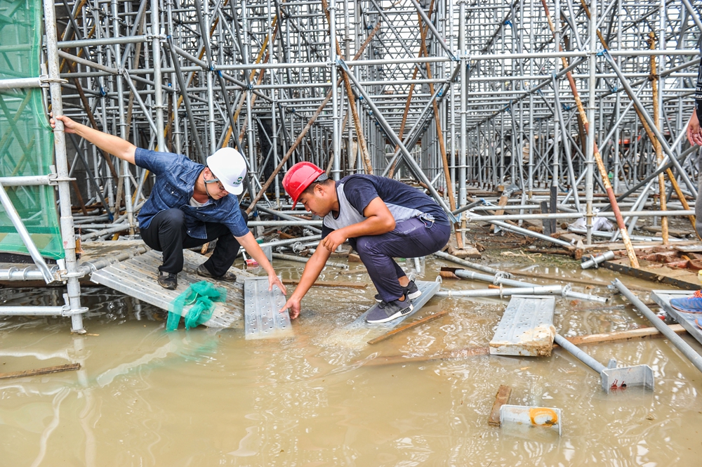 10 2017年8月22日，裴睿（左）正在工地的积水处和同事搭建简易踏板。.jpg