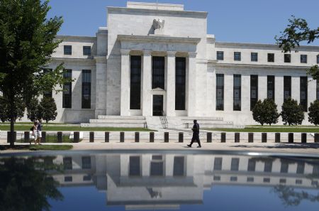 The U.S. Federal Reserve is reflected in a car as a security officer patrols the front of the building in Washington, June 24, 2009. 