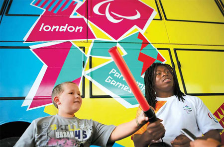Former British wheelchair basketball player Ade Adepitan and 9-year-old gymnast Gareth Picken, pose in front of the bus yesterday in Beijing.