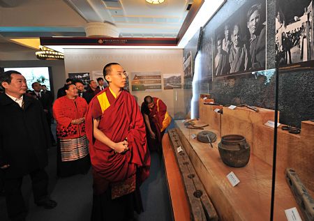 The 11th Panchen Lama Erdeni Gyaincain Norbu (front) looks at the exhibits during an exhibition titled "Democratic Reform in the Tibet Autonomous Region" in Beijing, capital of China, March 15, 2009. (Xinhua/Fan Rujun)