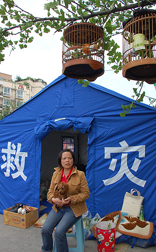A woman sits with her dog outside a tent given to her by the government as part of its relief work in Dujiangyan HUANG WEI/BEIJING REVIEW 