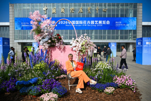 在展会的入口，一名外国观众在主题花坛前拍照留念.jpg