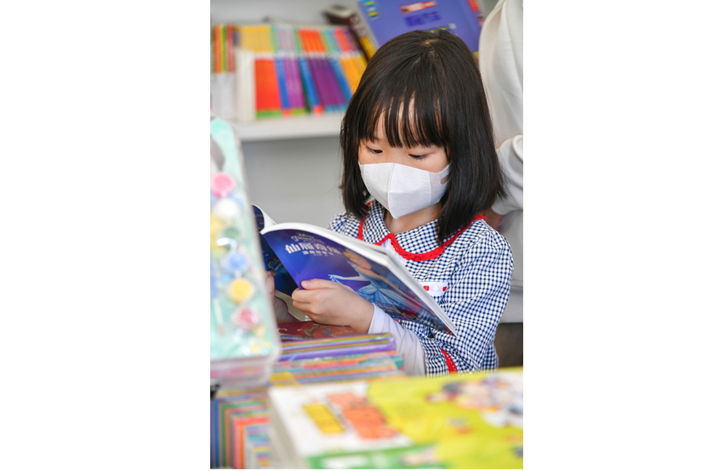 一位小读者在书市上看一本童书.JPG