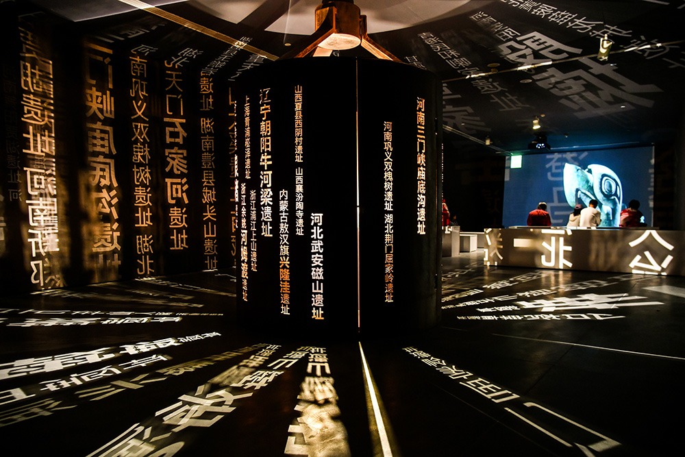 观众正在多媒体展厅欣赏相关纪录片，展厅里投射出此次展览所涉及的13个早期中华文明遗址名称.jpg