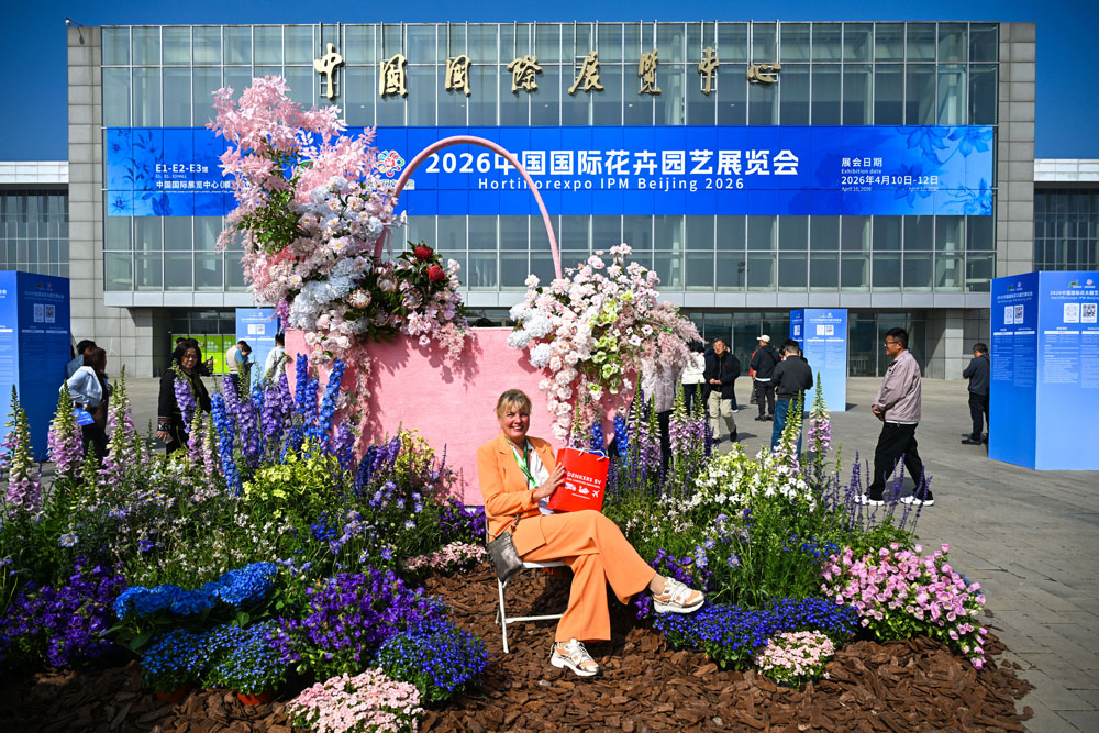 在展会的入口，一名外国观众在主题花坛前拍照留念.jpg