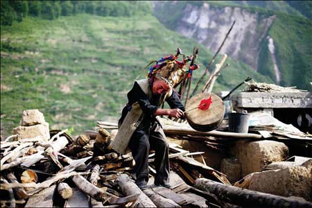 Wang Mingjie, a Qiang ethnic villager in Luobu village, prays on the ruins of his house.